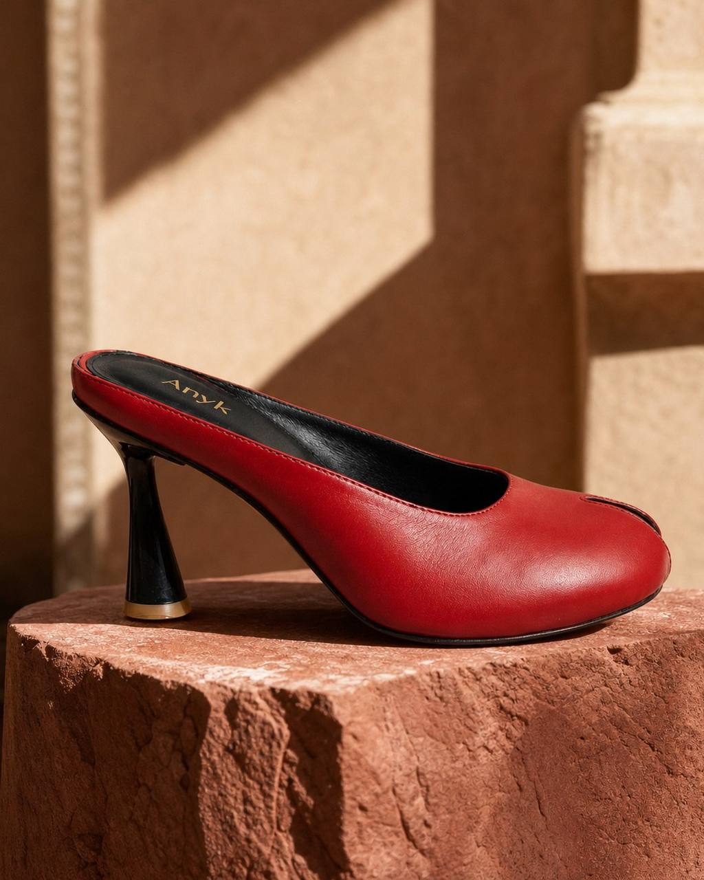 Red leather mule heel in warm architectural sunlight