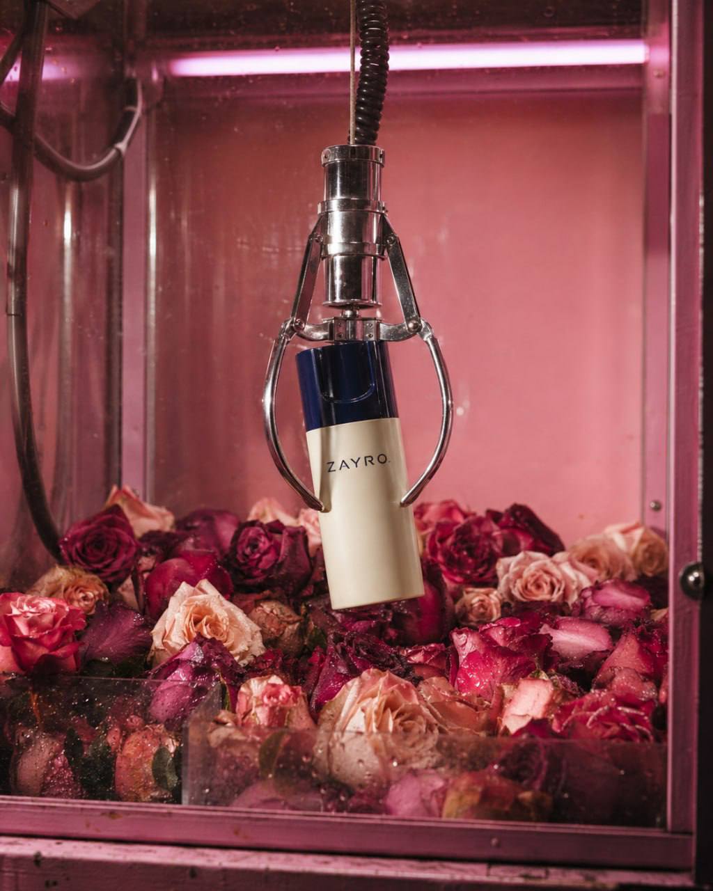 ZAYRO product suspended inside a pink claw machine filled with roses
